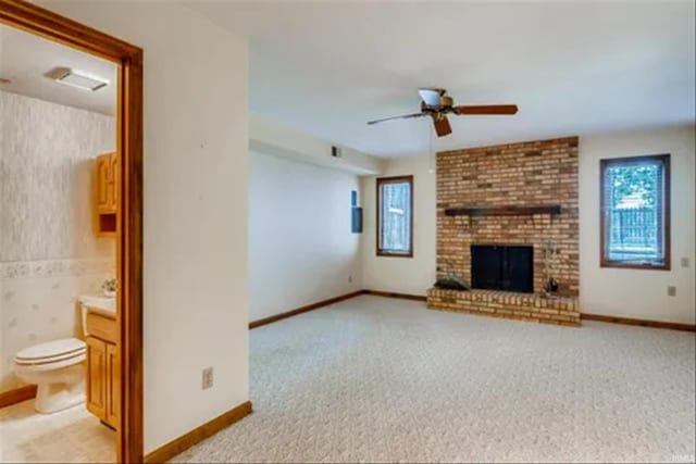 unfurnished living room with ceiling fan, light colored carpet, and a fireplace