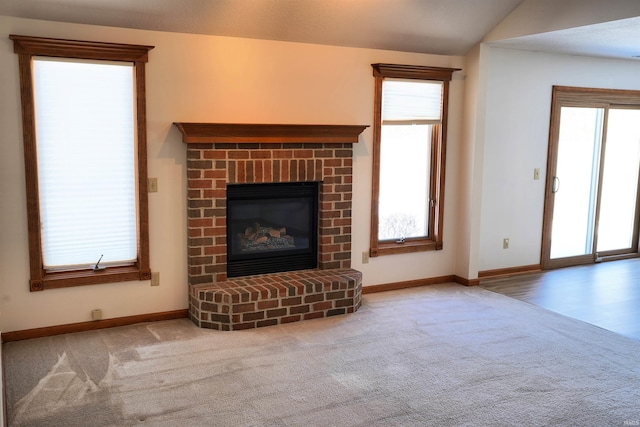 unfurnished living room featuring carpet floors, a brick fireplace, and vaulted ceiling