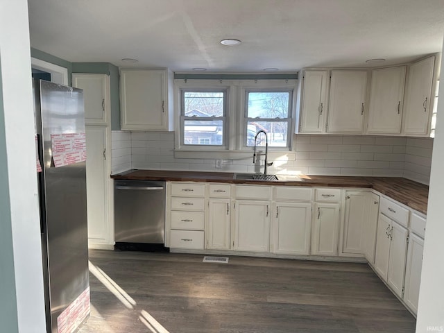 kitchen with backsplash, sink, dark wood-type flooring, stainless steel appliances, and white cabinets