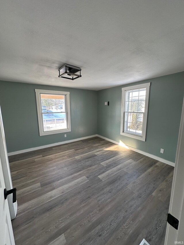 spare room featuring dark hardwood / wood-style flooring and a textured ceiling