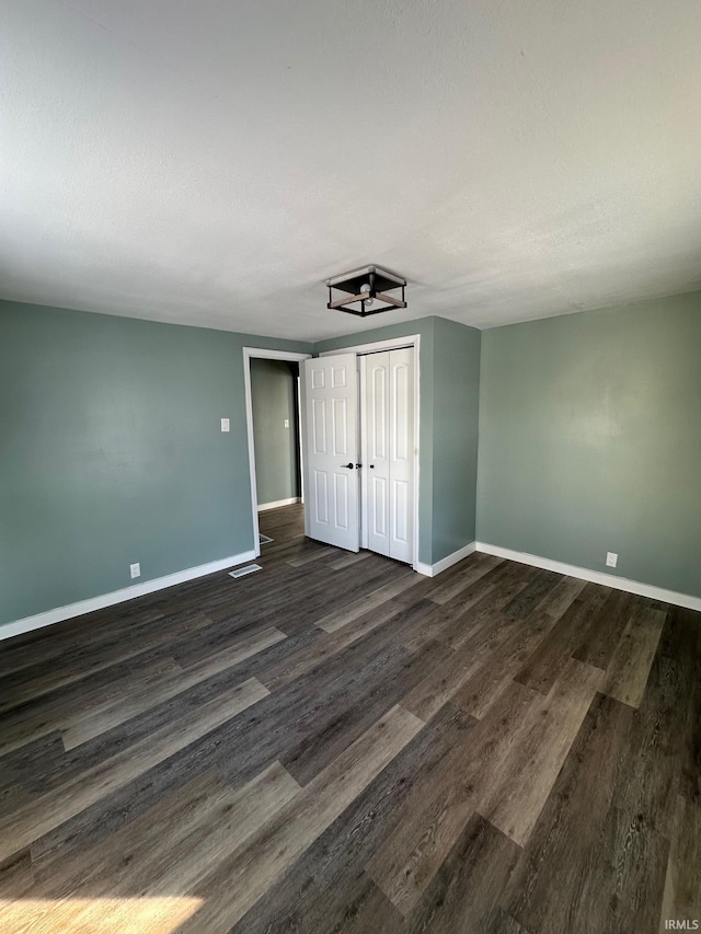 unfurnished bedroom with dark hardwood / wood-style flooring and a closet