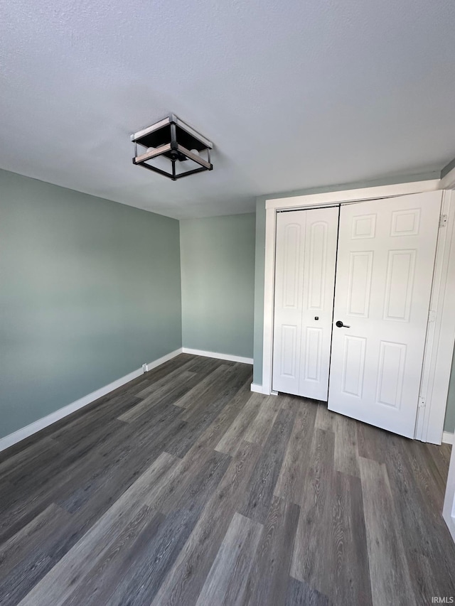 unfurnished bedroom with a textured ceiling, a closet, and dark hardwood / wood-style floors