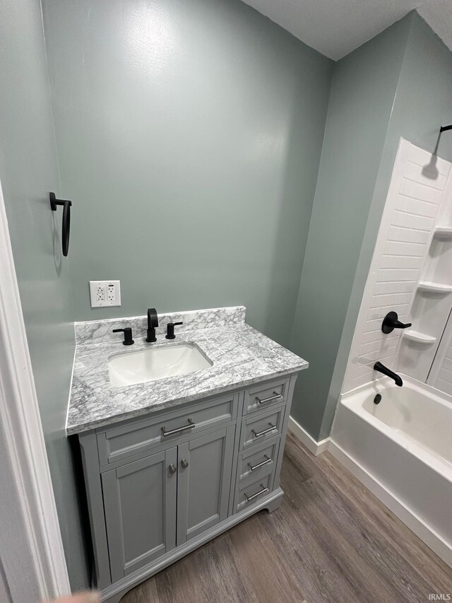 bathroom featuring hardwood / wood-style floors, vanity, and  shower combination