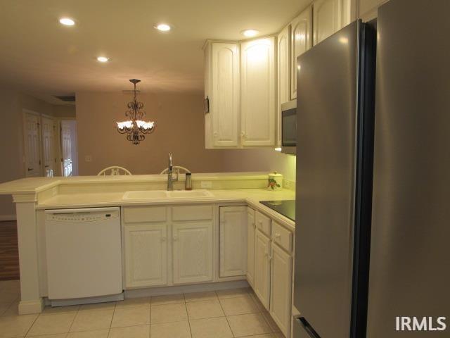 kitchen featuring decorative light fixtures, kitchen peninsula, stainless steel appliances, light tile patterned floors, and a chandelier