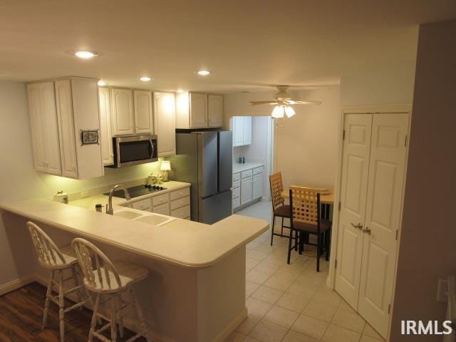 kitchen with appliances with stainless steel finishes, sink, a kitchen breakfast bar, kitchen peninsula, and ceiling fan