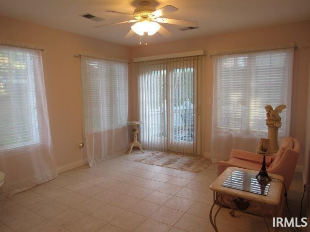 doorway featuring ceiling fan, light tile patterned floors, and a healthy amount of sunlight