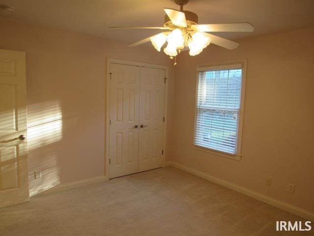 unfurnished bedroom with light carpet, ceiling fan, and a closet