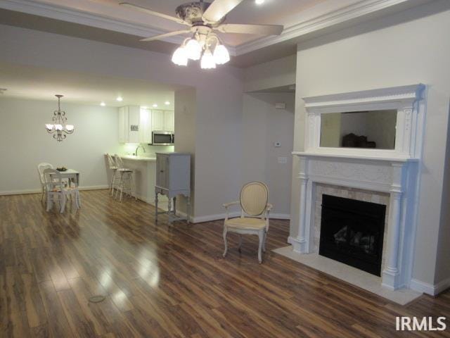 living room with dark hardwood / wood-style floors, ceiling fan with notable chandelier, and ornamental molding