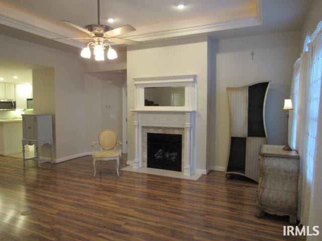 living room with ceiling fan, dark hardwood / wood-style floors, and a tray ceiling