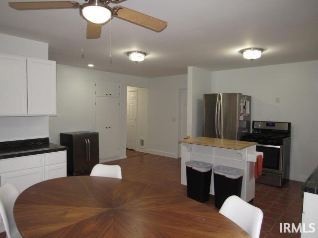 kitchen featuring butcher block counters, a kitchen island, stainless steel appliances, and white cabinetry