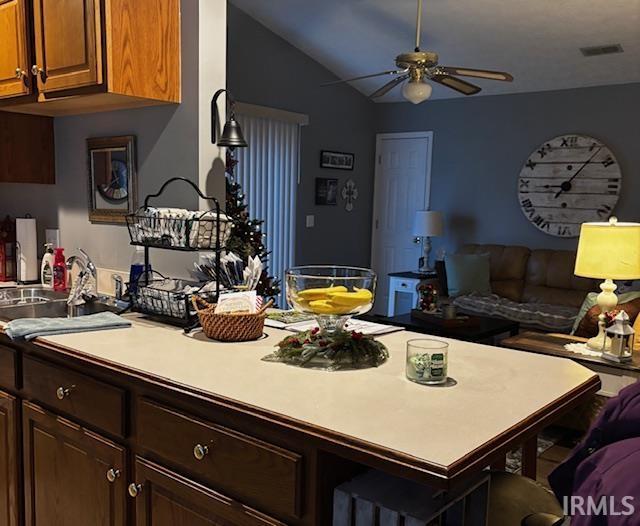 kitchen featuring ceiling fan, lofted ceiling, a kitchen bar, and sink