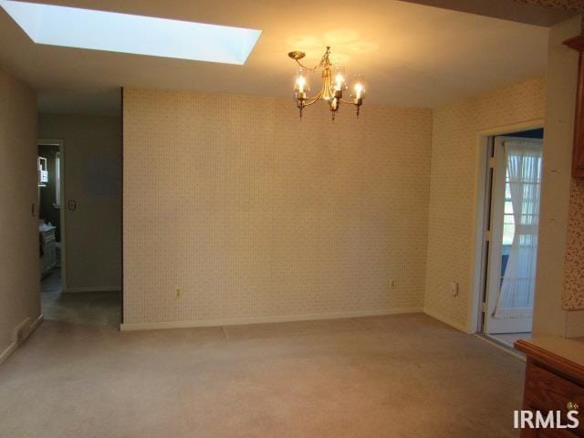 unfurnished room featuring carpet floors, a skylight, and a chandelier