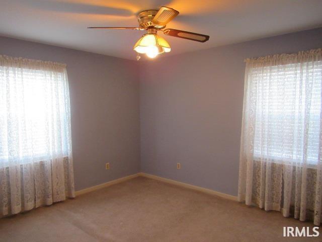 carpeted spare room with ceiling fan