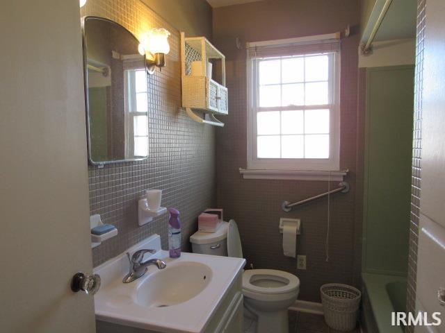 bathroom with vanity, toilet, and a tub