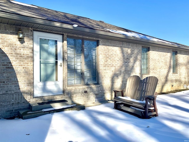 snow covered property entrance with a patio