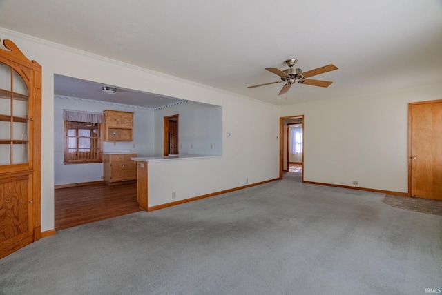 unfurnished living room featuring ceiling fan, crown molding, and light colored carpet