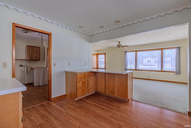 kitchen with light wood-type flooring, ceiling fan, and kitchen peninsula