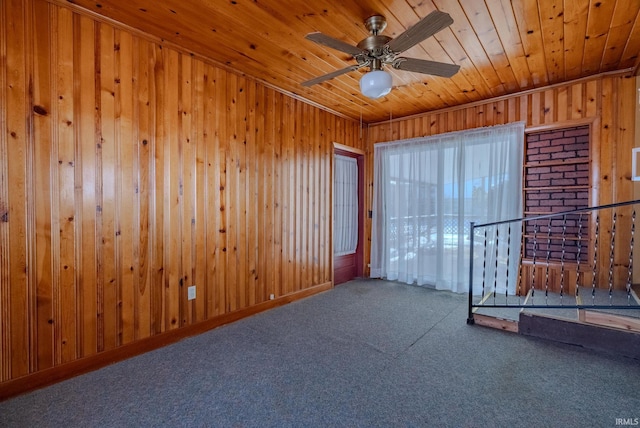 empty room featuring wooden ceiling, carpet flooring, wooden walls, and ceiling fan