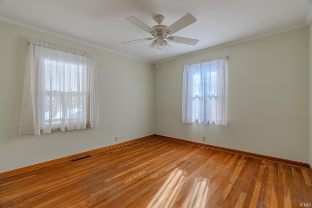 empty room featuring ornamental molding, a healthy amount of sunlight, and light hardwood / wood-style floors