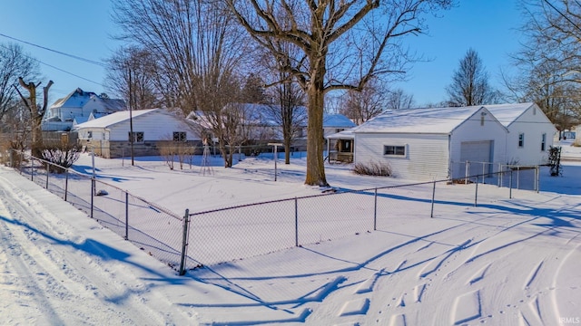 snowy yard with a garage and an outbuilding