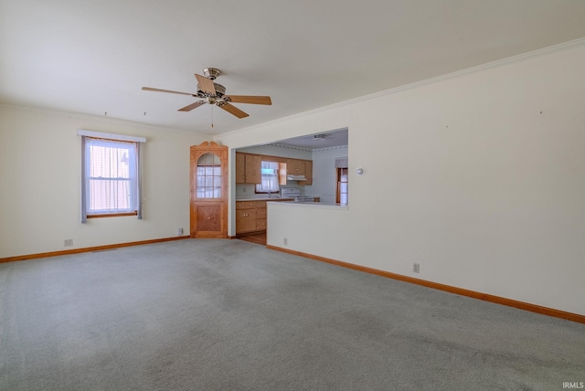 unfurnished living room with ceiling fan, ornamental molding, and light colored carpet