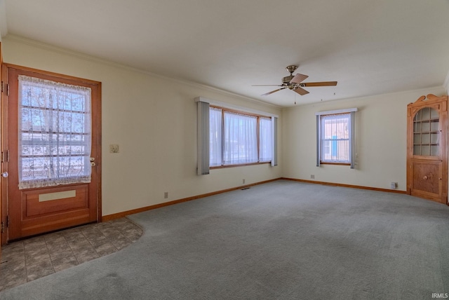 unfurnished living room with ceiling fan, ornamental molding, and carpet flooring