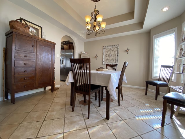 tiled dining area featuring an inviting chandelier and a raised ceiling