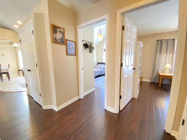 hall with dark hardwood / wood-style flooring and a notable chandelier