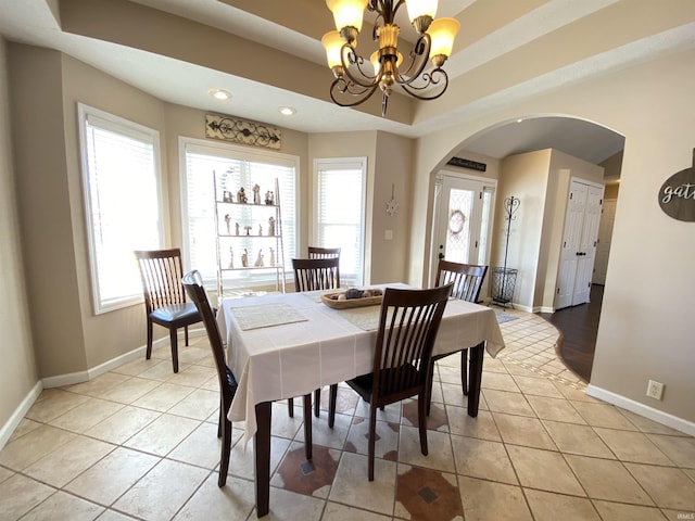 tiled dining space with a tray ceiling and an inviting chandelier