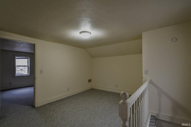 additional living space with a textured ceiling and vaulted ceiling