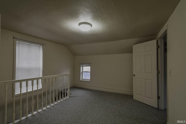 bonus room with vaulted ceiling, carpet flooring, and a textured ceiling