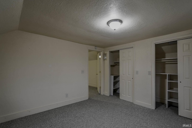 unfurnished bedroom featuring two closets, a textured ceiling, lofted ceiling, and carpet