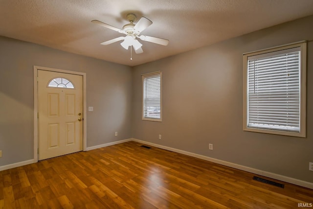 entryway with ceiling fan, a textured ceiling, and hardwood / wood-style flooring