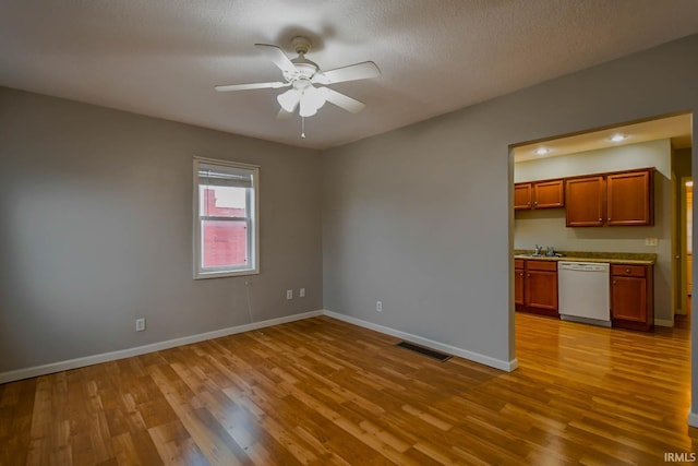 spare room featuring light wood-type flooring, ceiling fan, a textured ceiling, and sink