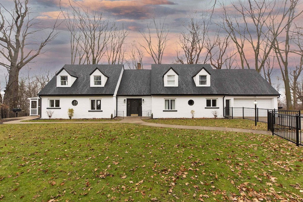 cape cod home with a garage and a lawn