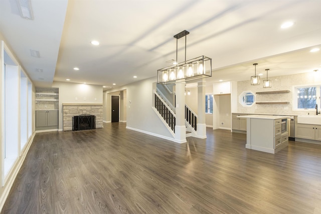 unfurnished living room featuring dark hardwood / wood-style flooring, a stone fireplace, and sink