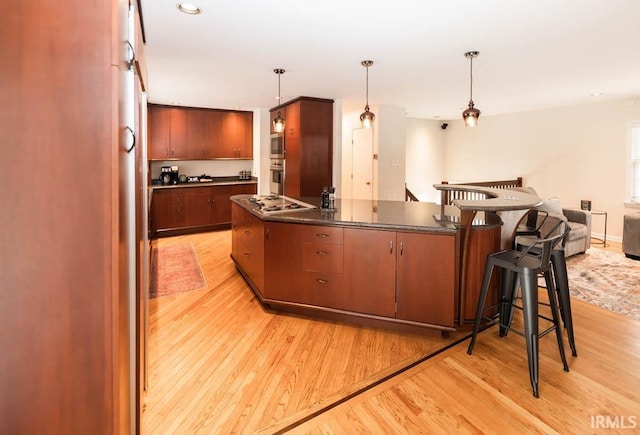 kitchen featuring pendant lighting, appliances with stainless steel finishes, a breakfast bar area, and light wood-type flooring