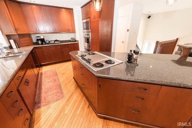 kitchen featuring appliances with stainless steel finishes, sink, stone countertops, and light hardwood / wood-style floors