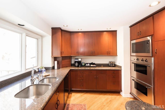 kitchen featuring sink, stone countertops, stainless steel appliances, and light wood-type flooring