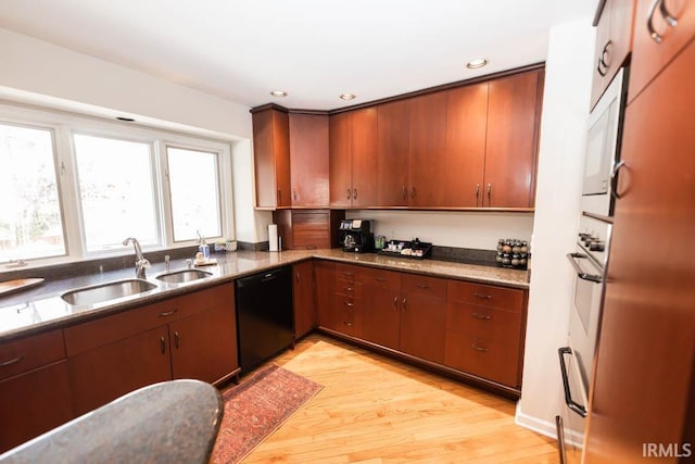 kitchen with black dishwasher, light hardwood / wood-style flooring, and sink