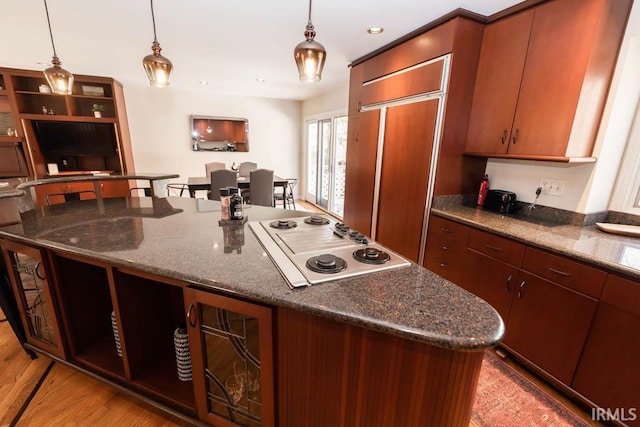 kitchen with light hardwood / wood-style floors, white cooktop, pendant lighting, and dark stone counters