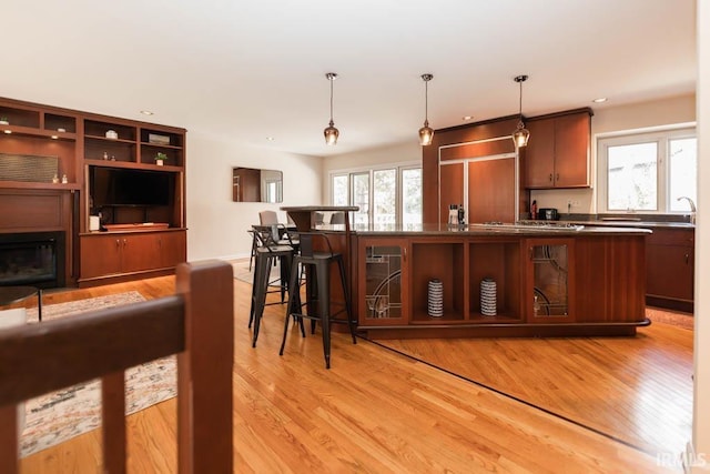 kitchen featuring light hardwood / wood-style floors, pendant lighting, paneled fridge, and a breakfast bar area