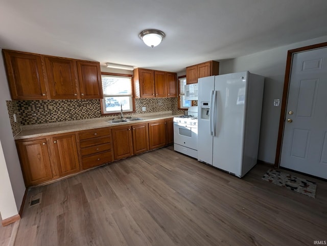 kitchen with sink, white appliances, tasteful backsplash, and light wood-type flooring