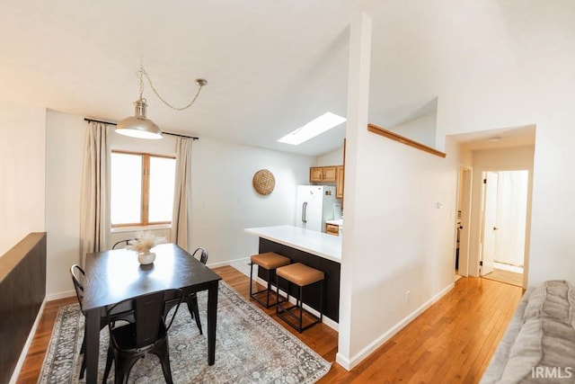 dining space with light hardwood / wood-style floors and lofted ceiling with skylight