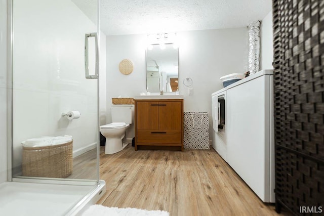 bathroom featuring toilet, a shower with door, wood-type flooring, a textured ceiling, and vanity