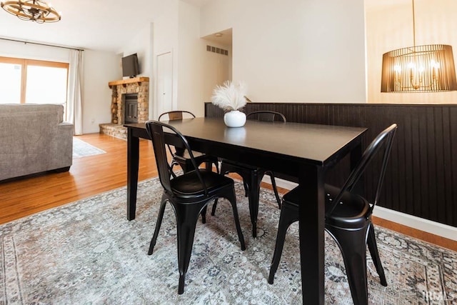 dining space with a chandelier, a fireplace, and wood-type flooring