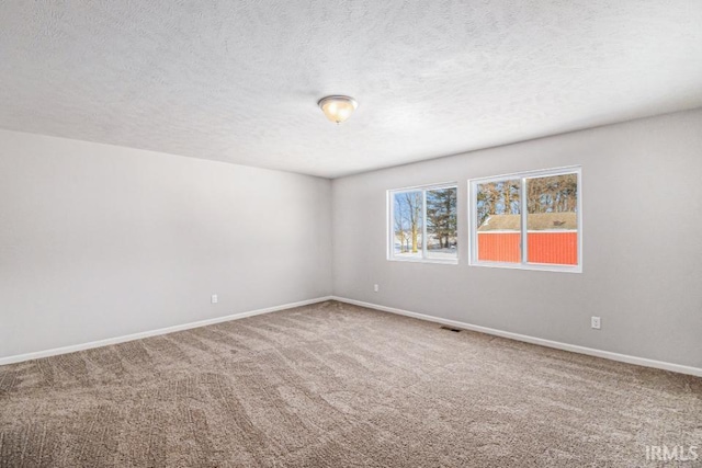 carpeted spare room featuring visible vents, baseboards, and a textured ceiling