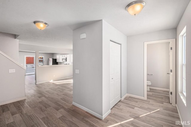 hall with plenty of natural light, baseboards, and wood finished floors