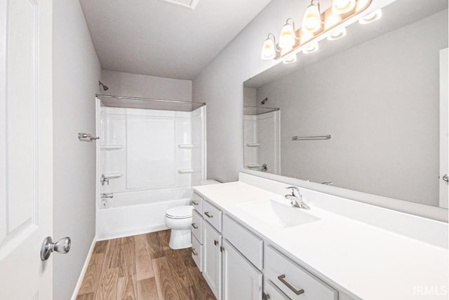 full bathroom featuring baseboards, toilet, wood finished floors, vanity, and shower / washtub combination