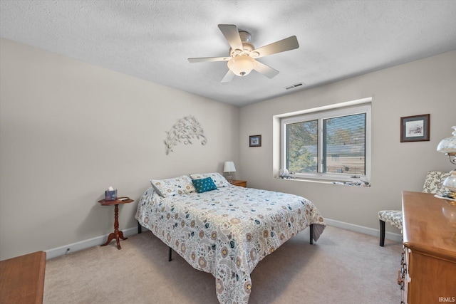 bedroom featuring a textured ceiling, ceiling fan, and light colored carpet